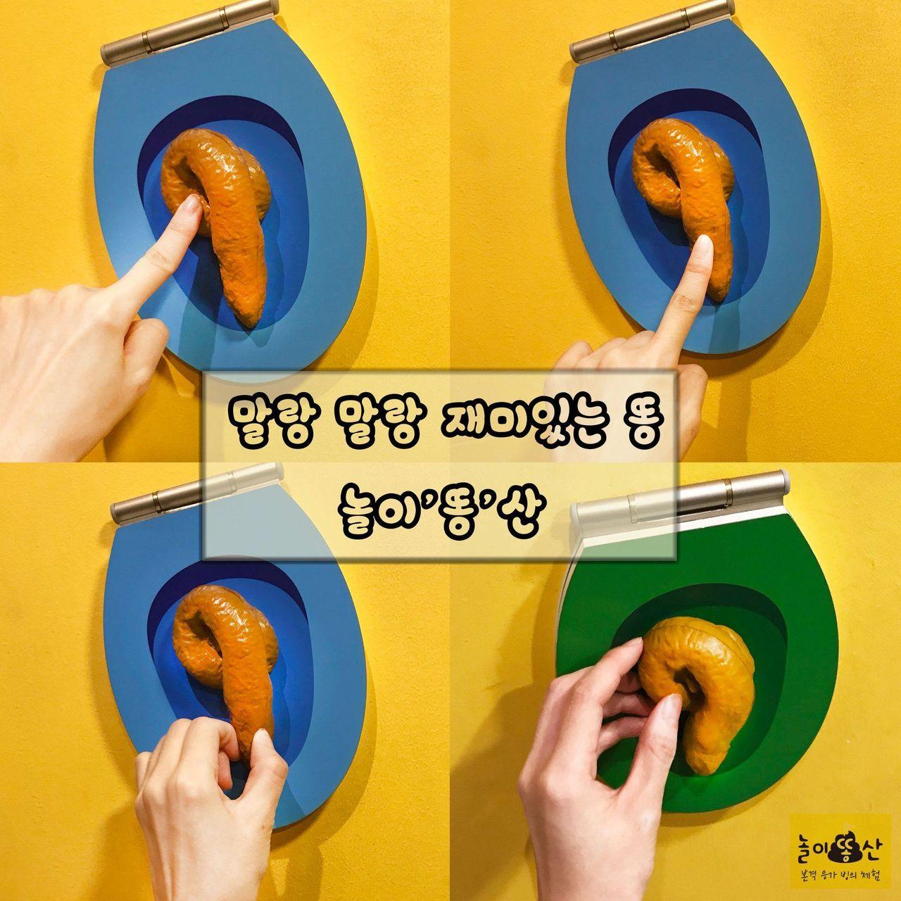 韓國大便展覽，兩位遊客在互動裝置上進行拍照，背景是色彩鮮豔的牆壁。